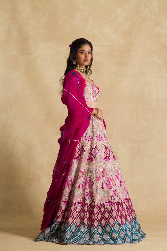Woman in magenta and cream embroidered lehenga with floral dupatta, beige background