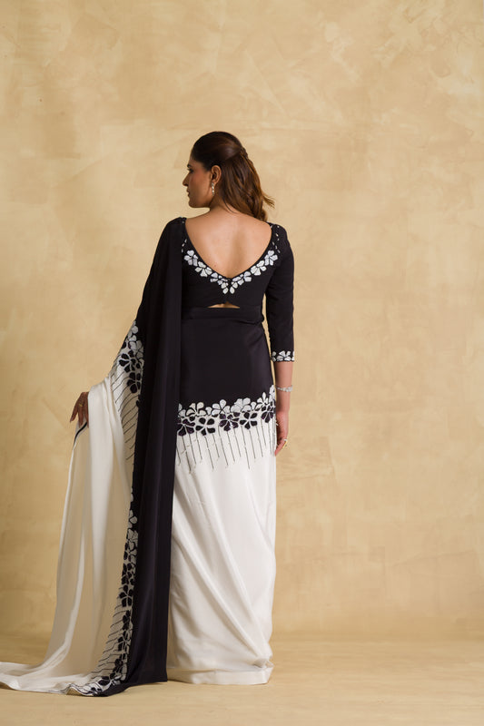 Woman in black and white floral embroidered saree with deep back blouse, neutral background