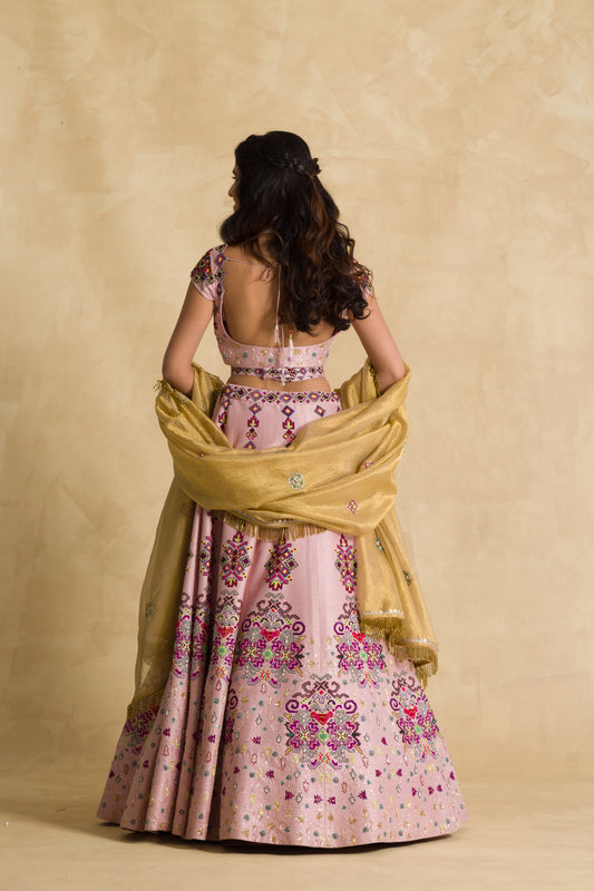 Woman in pink embroidered lehenga and gold dupatta with open back blouse, back view
