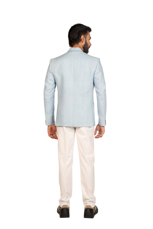 Man in light blue blazer and white trousers facing away on white background