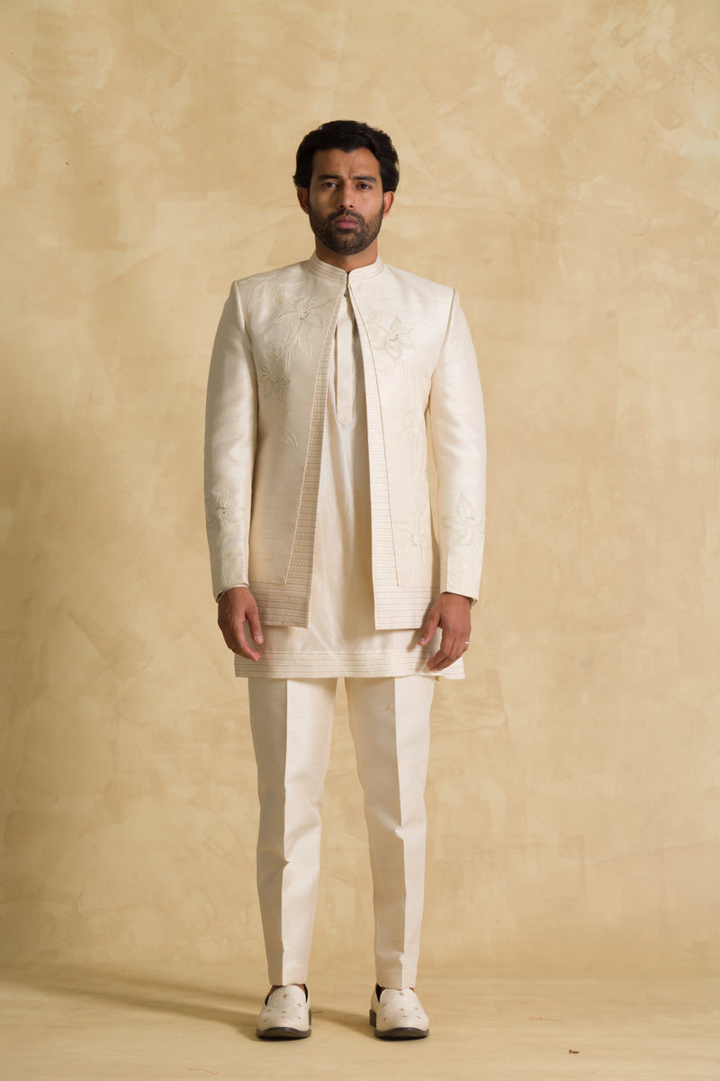 Man wearing cream embroidered sherwani suit with matching pants, neutral background
